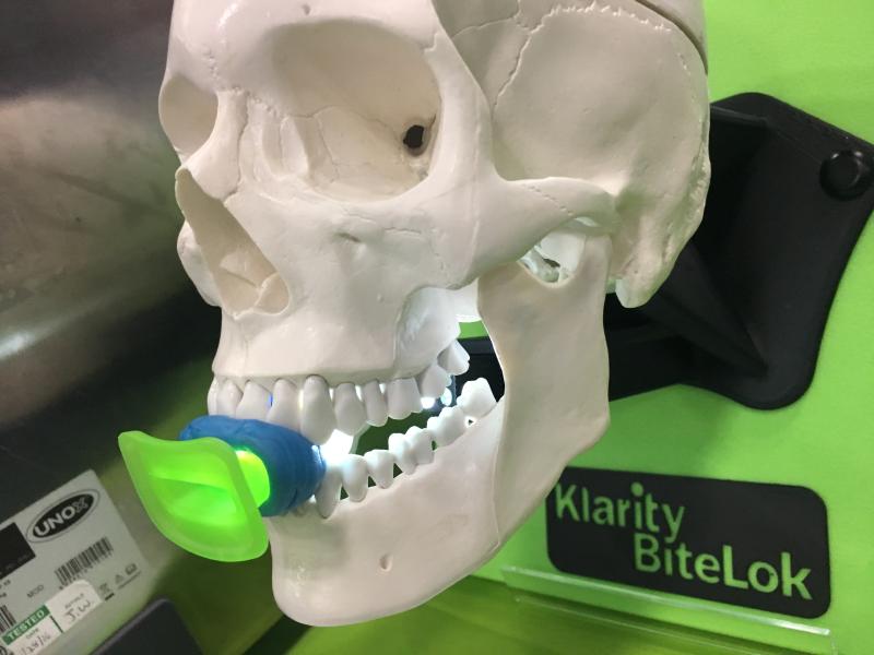 This is a new radiation oncology tongue immobilization device to prevent motion or variations in head or neck tumor positions during treatments. The Klarity BiteLok device is being displayed on the expo floor of the 2019 American Association of Physicists in Medicine (AAPM) meeting. It uses standard dental putty to mold to the patients mouth, and a clip to hold the mount in place as the head immobilization mask is molded. The mouth piece can be removed from the mask for cleaning.