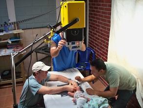 Doctors use a MinXray unit to capture an image of an infant with a clubfoot.