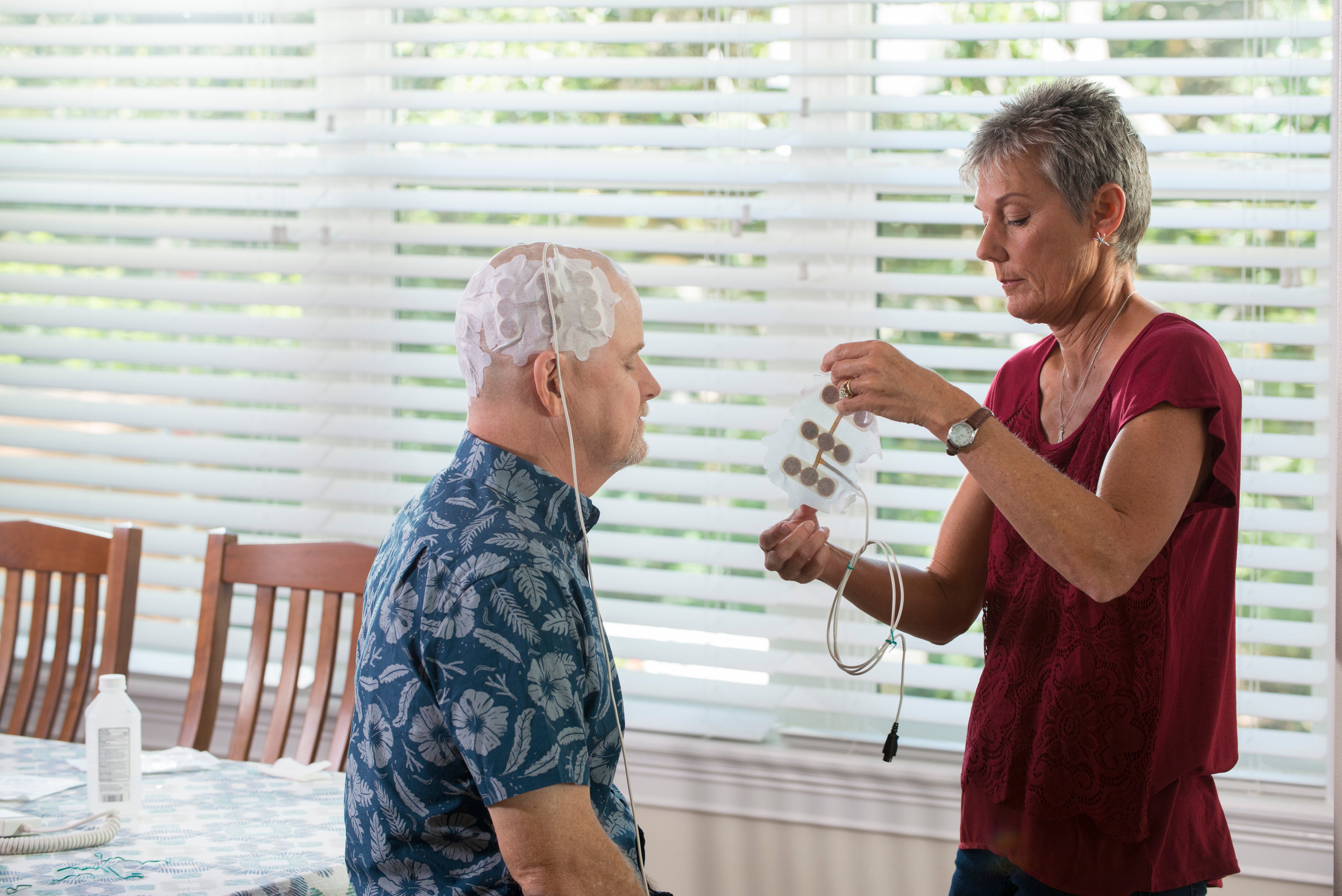 The patient’s wife changes the Optune array. Clinical trials indicate that the electrical fields emitted by Optune have the potential to lengthen the lives of patients with glioblastoma.