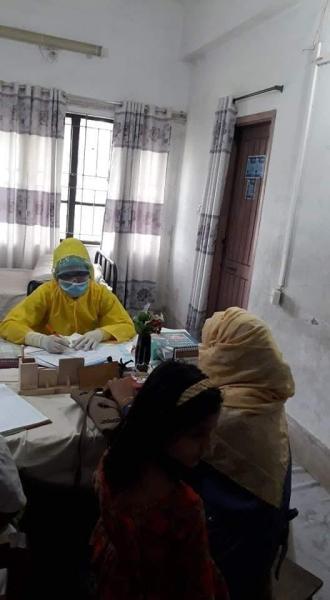 A doctor in their office in Bangladesh wearing full personal protective equipment (PPE) in between seeing patients. The cot behind the doctor is because of the long shifts they are required to do because of the shortage of doctors during the COVID-19 pandemic. Photo by Aster Azalea.