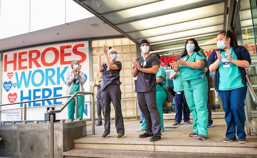 Signs for "Heroes work here" outside healthcare facilities and even the homes of clinicians have popped up across the country. This photo shows healthcare workers at the Lenox Health emergency room entrance being greeted to cheers and thanks for their essential service during the COVID-19 pandemic in New York City at a public thank you event May 21, 2020.